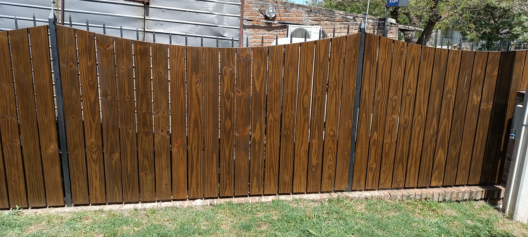 Cerco de madera lustrada con postes de hierro en jardin