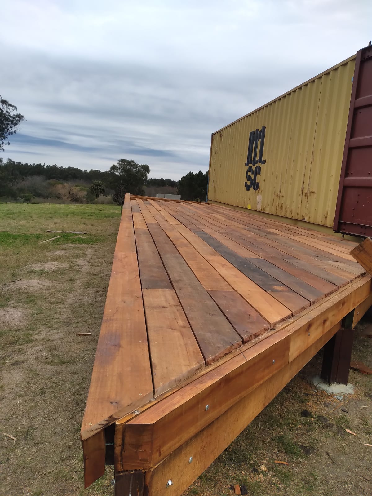 Deck de madera terminado junto a contenedor en campo