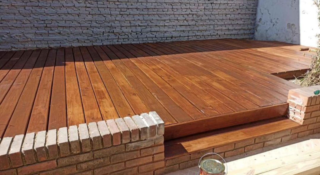 Deck de madera lustrada con borde de ladrillo, lata de barniz