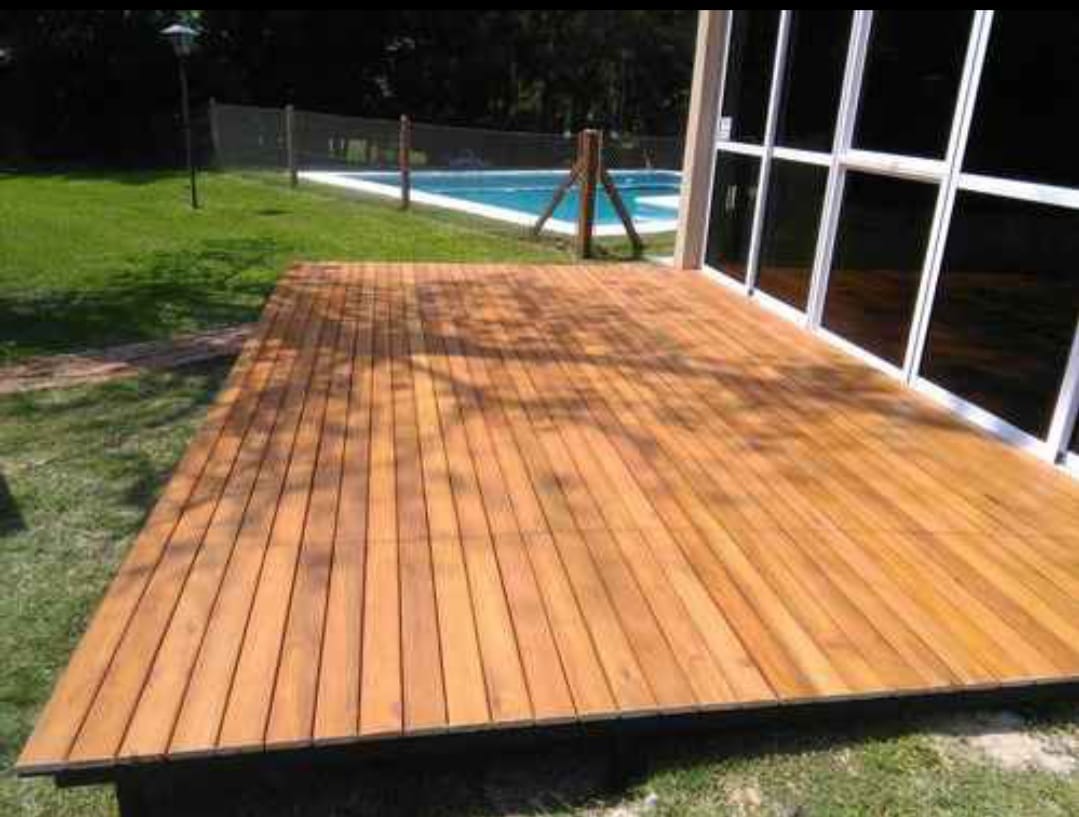 Deck de madera clara junto a casa con piscina y cesped