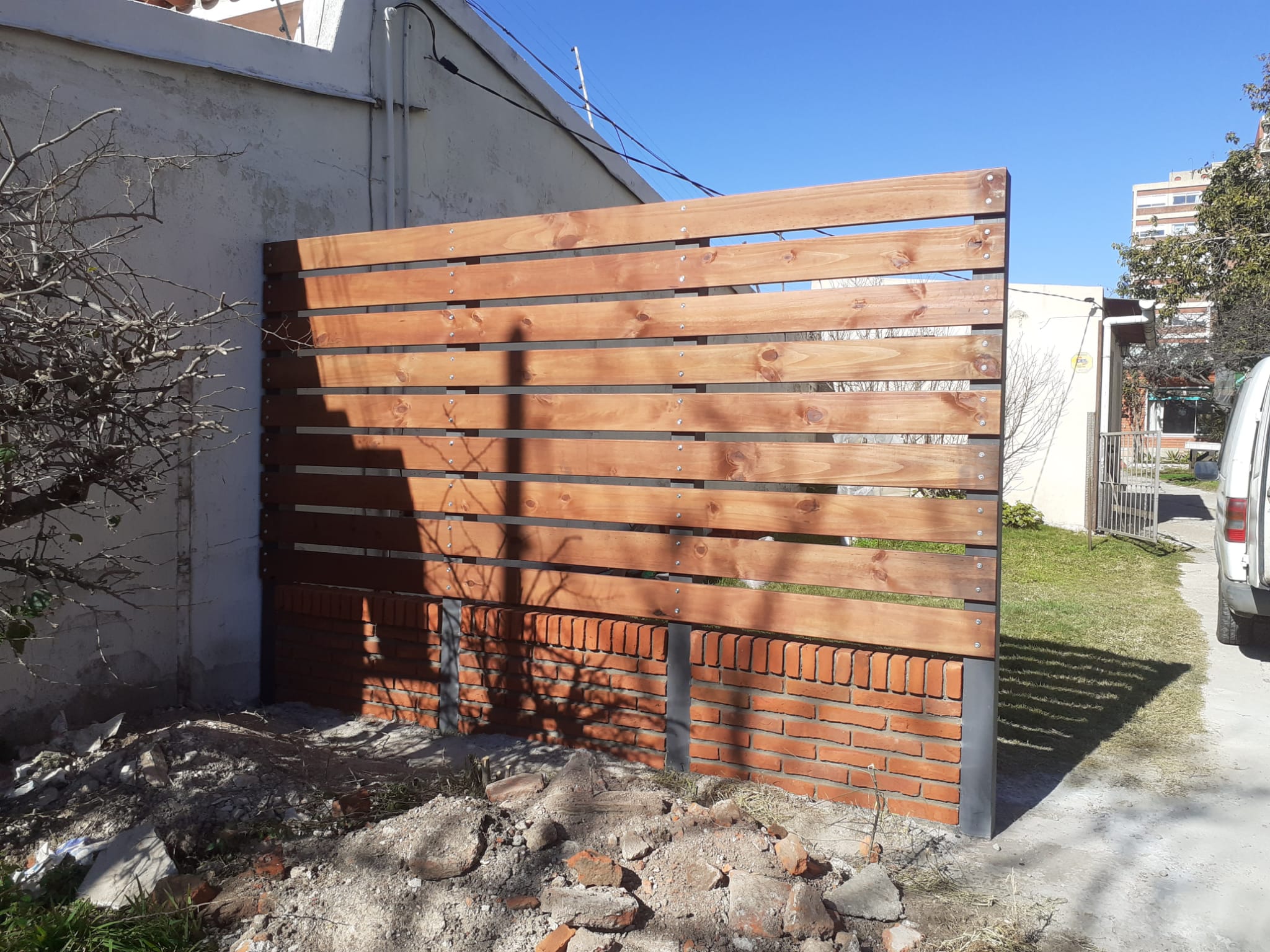 Cerco cortasol de madera y hierro sobre base de ladrillo