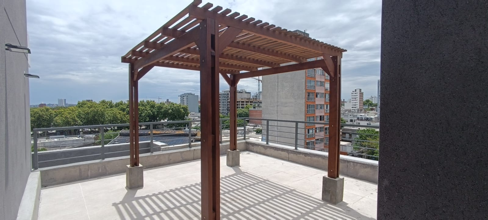 Pérgola de madera terminada en azotea con cielo nublado