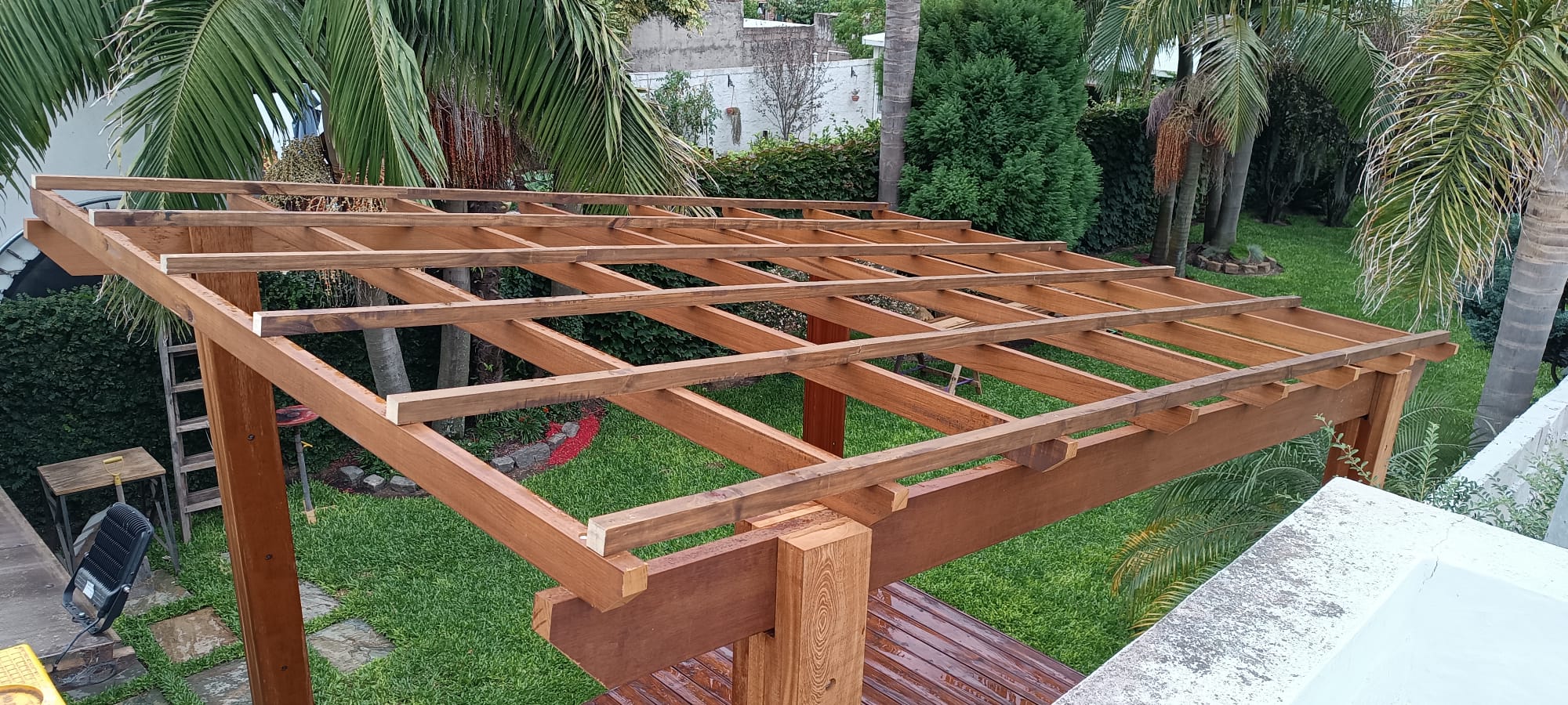 Estructura de pérgola de madera terminada sobre deck, jardín