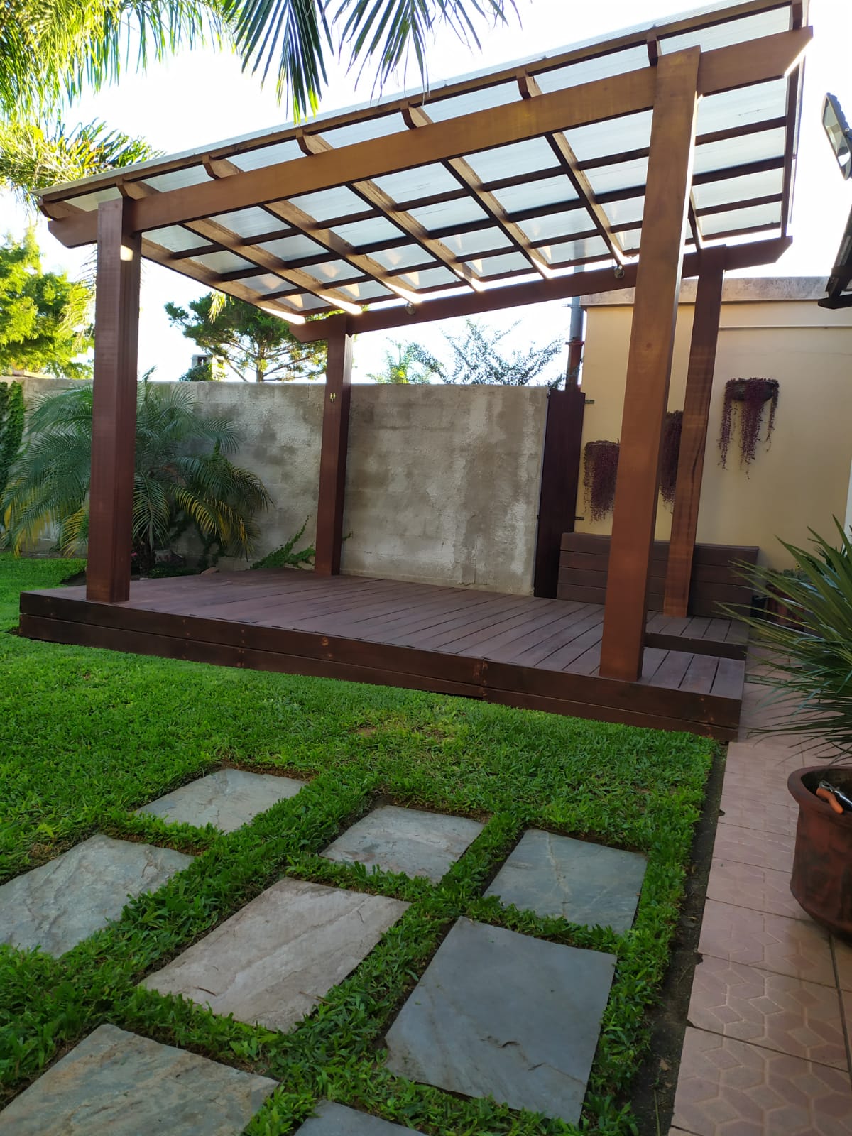 Pérgola de madera con techo policarbonato sobre deck, jardín