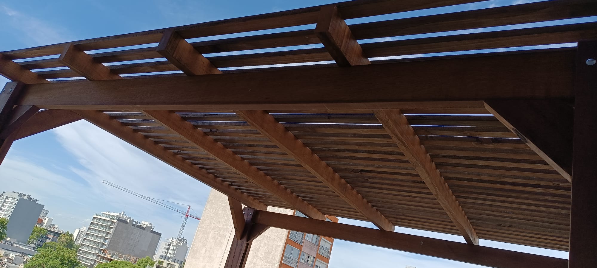 Pergola de madera vista desde abajo en terraza con vista urbana