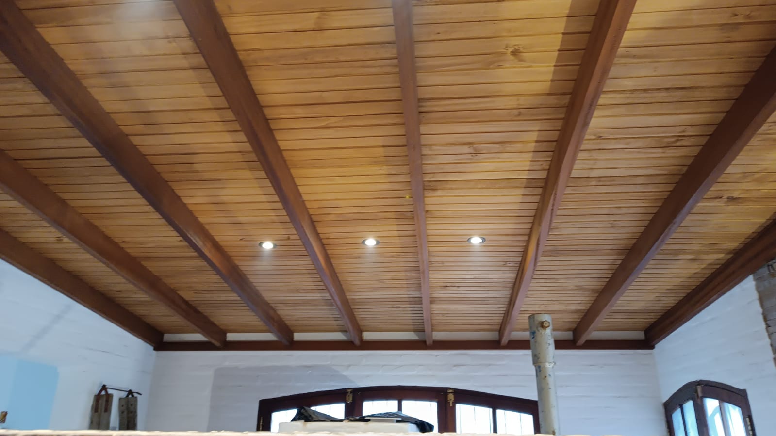 Techo de madera machimbrada con vigas y luces embutidas