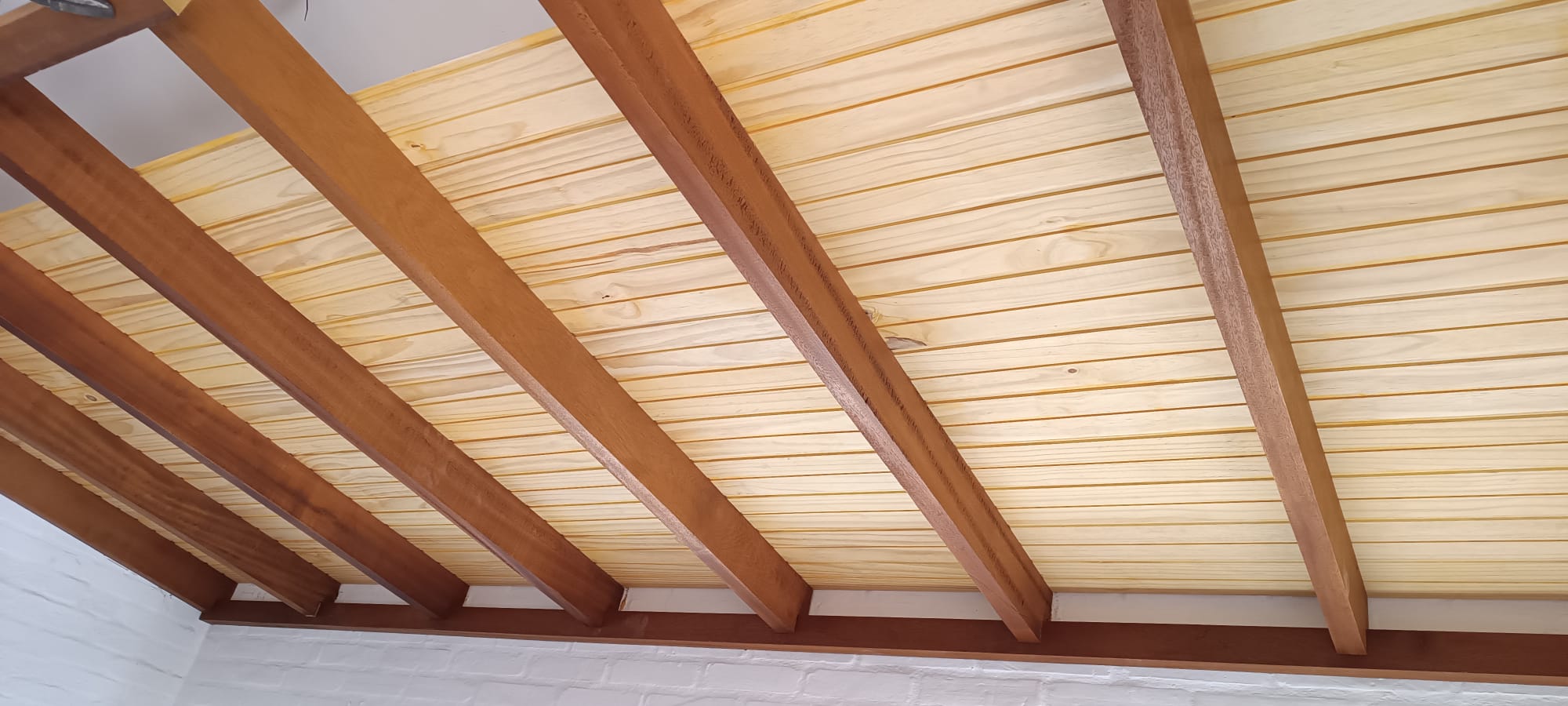 Cielorraso de machimbre de pino con vigas de madera barnizada