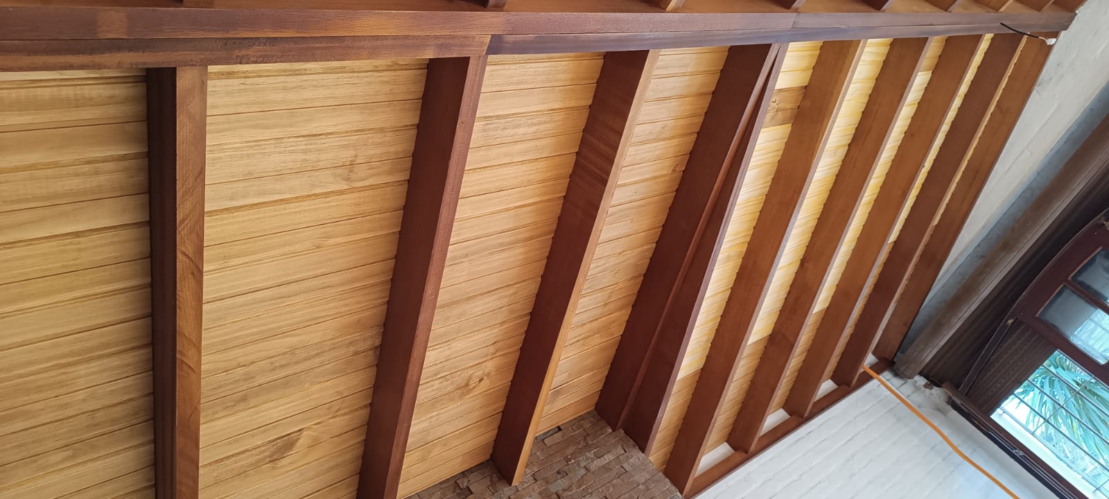 Detalle de techo de madera machimbrado con vigas inclinadas